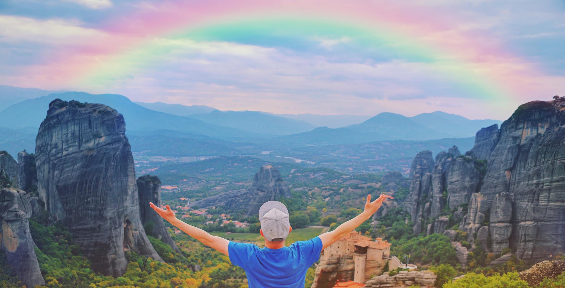 Man standing in front of mountains while opening his arms wide